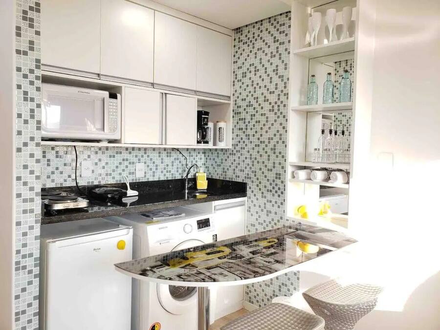 Una cocina compacta con microondas, estufa y lavamanos.