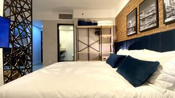 Quarto de hotel moderno com uma cama grande, um guarda-roupa e vista para a cidade pela janela.