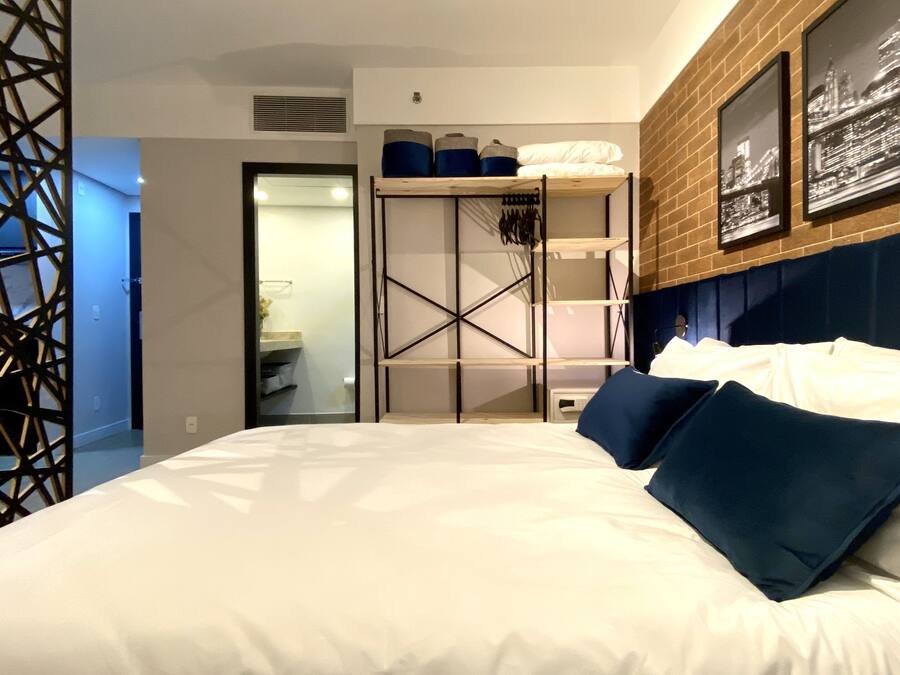 Quarto de hotel moderno com uma cama grande, um guarda-roupa e vista para a cidade pela janela.