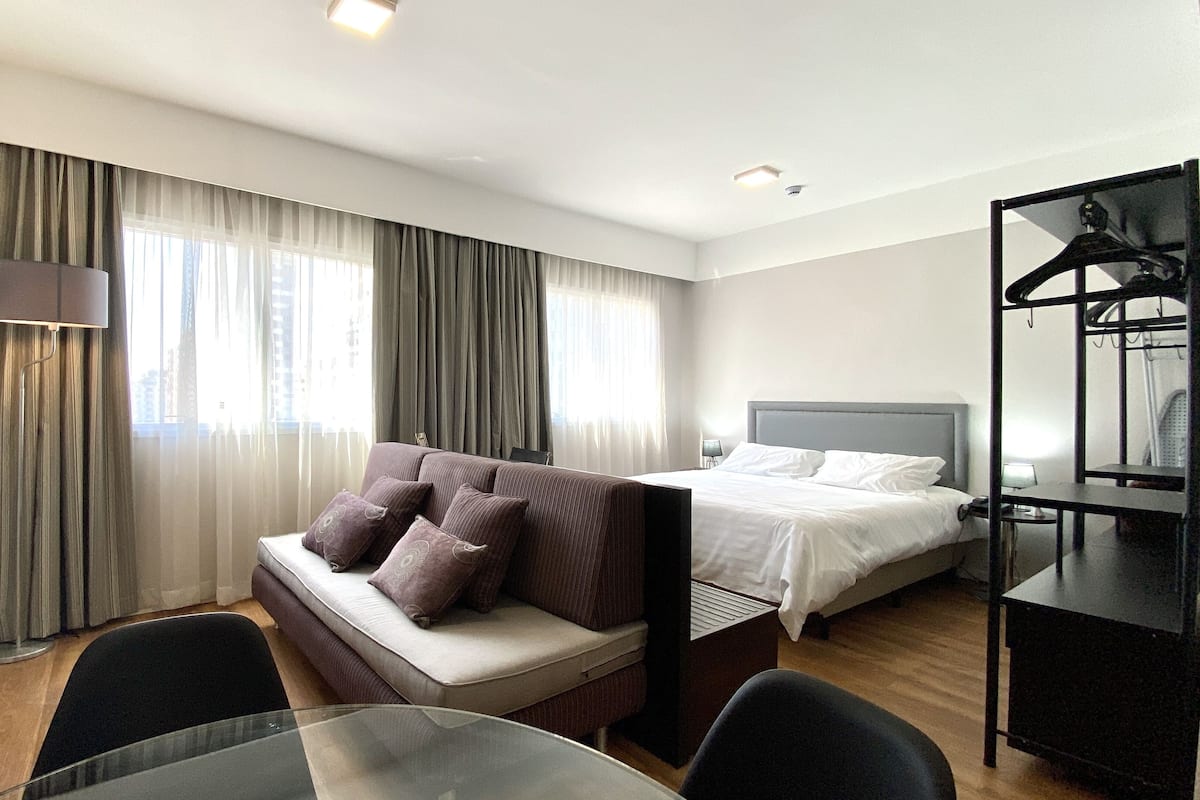 Hotellihuone, jossa on sänky, sohva, työpöytä ja televisio.