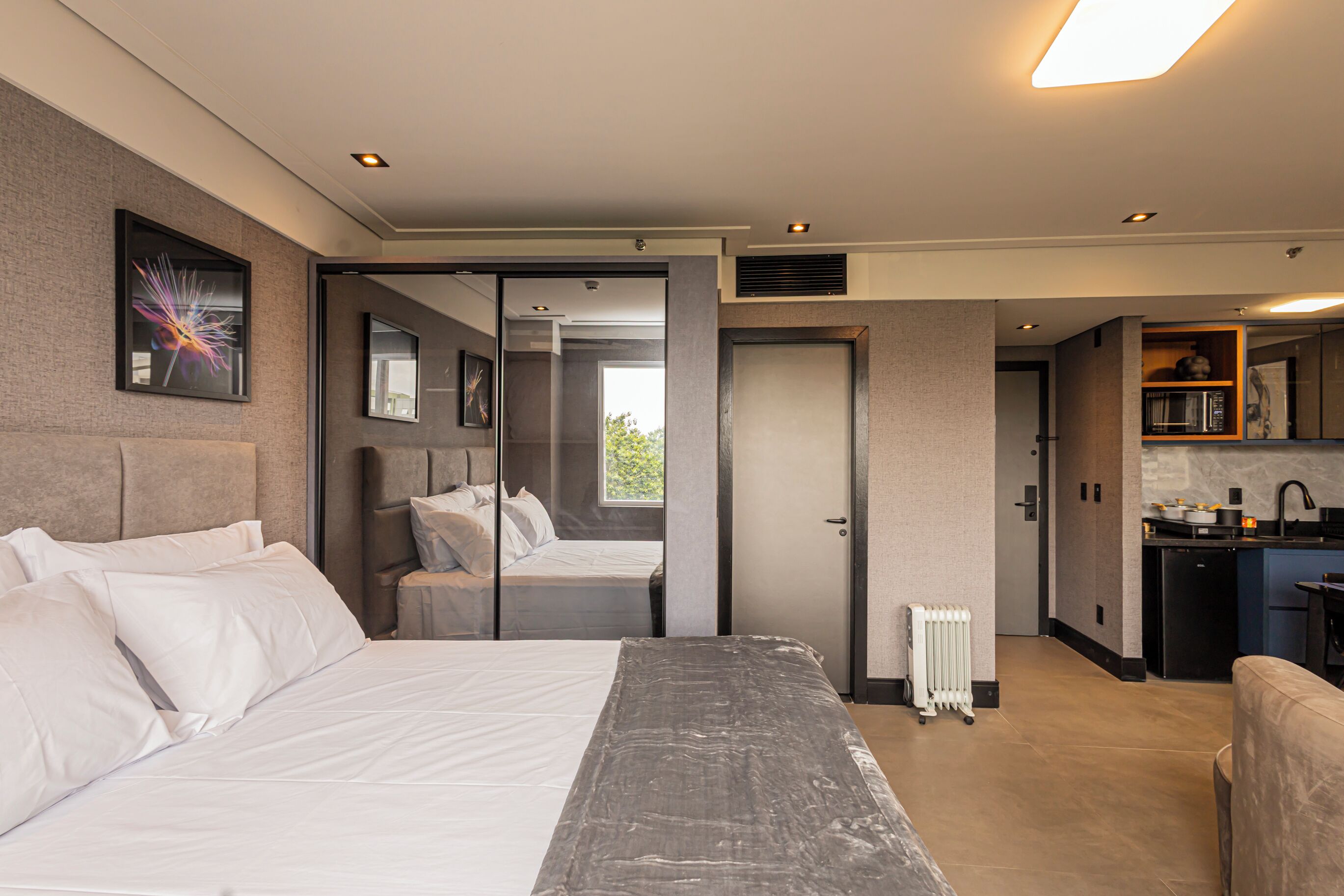 Une chambre moderne avec un grand lit, un petit coin salon et une kitchenette.