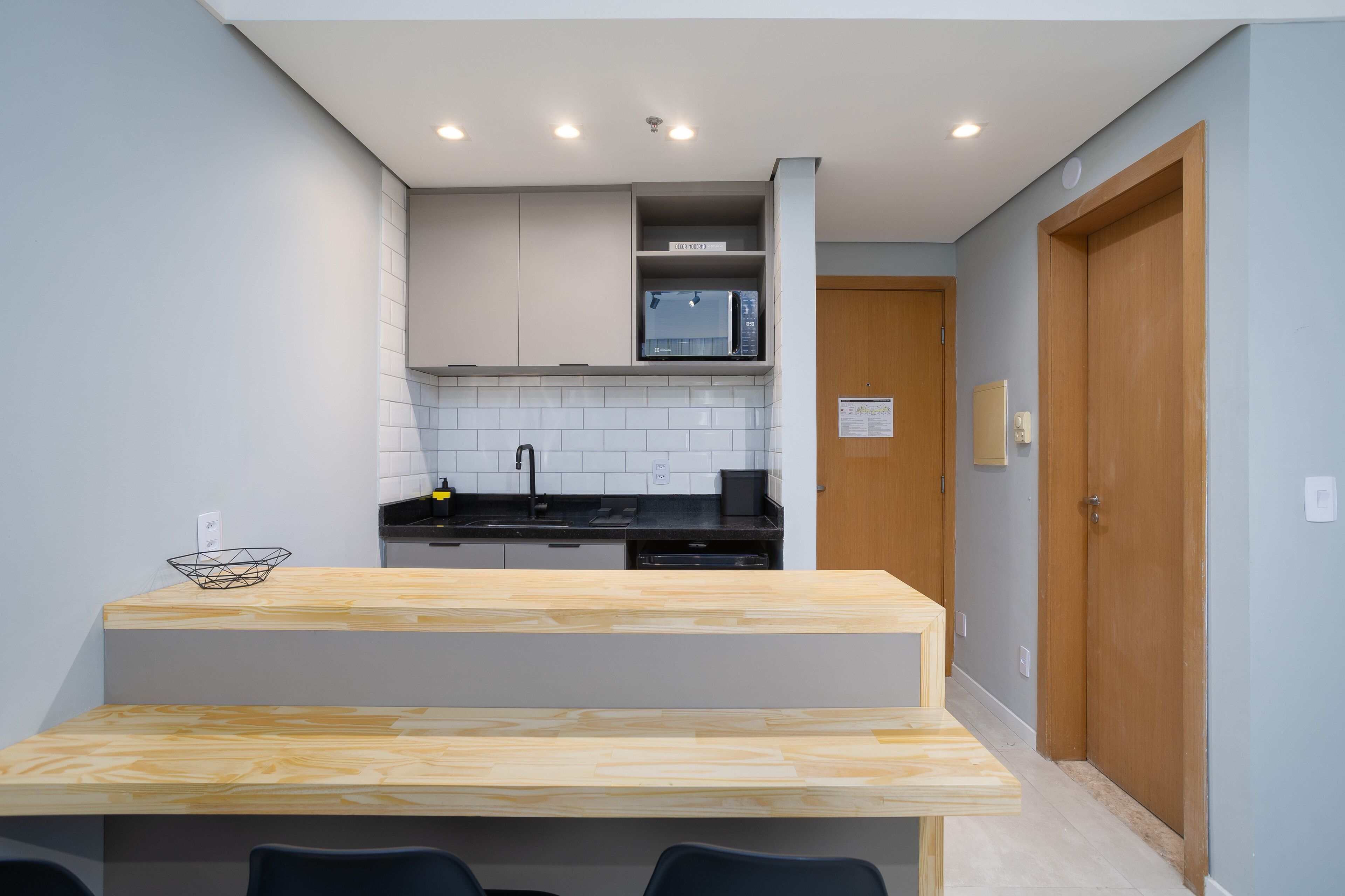 Une cuisine moderne dotée d’un îlot central en bois, d’un dosseret de carreaux blancs et d’appareils électroménagers intégrés.