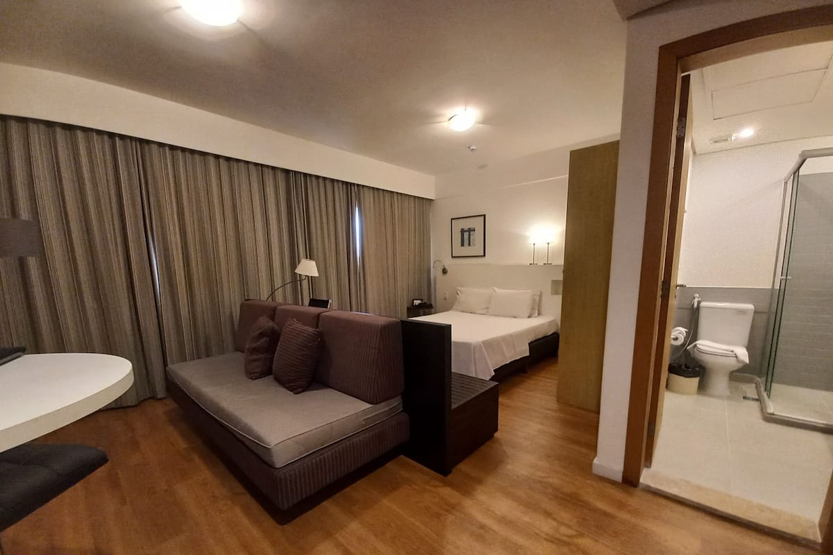Hotellihuone, jossa on sohva, sänky, työpöytä ja kylpyhuone.