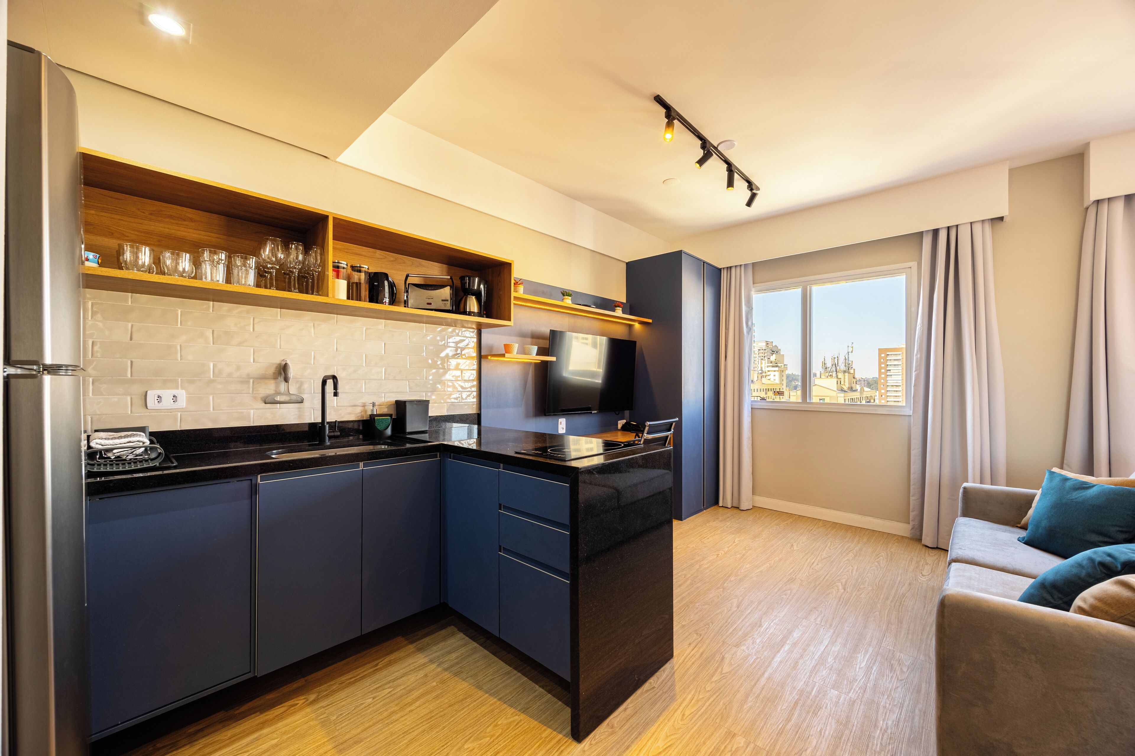 A modern kitchen with a built-in island, wooden shelves, and a city view through the window.