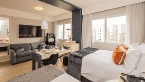 Una habitación de hotel moderna con una cama, un escritorio, un sofá y un televisor.