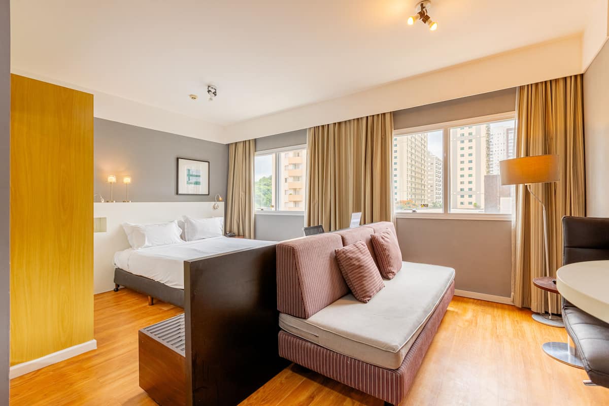 Moderni hotellihuone, jossa on sänky, sohva ja ruokailutila.