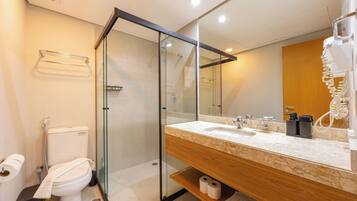 Un baño moderno con ducha envuelta en vidrio, tocador de madera y un espejo grande.