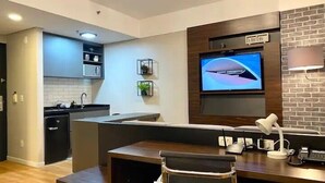 Una cocina moderna con una isla integrada, una zona de comedor con banco y un televisor montado en la pared.