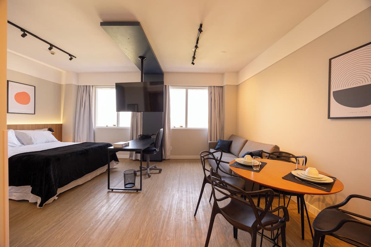 Hotellihuone, jossa on sänky, työpöytä, sohva ja ruokapöytä.