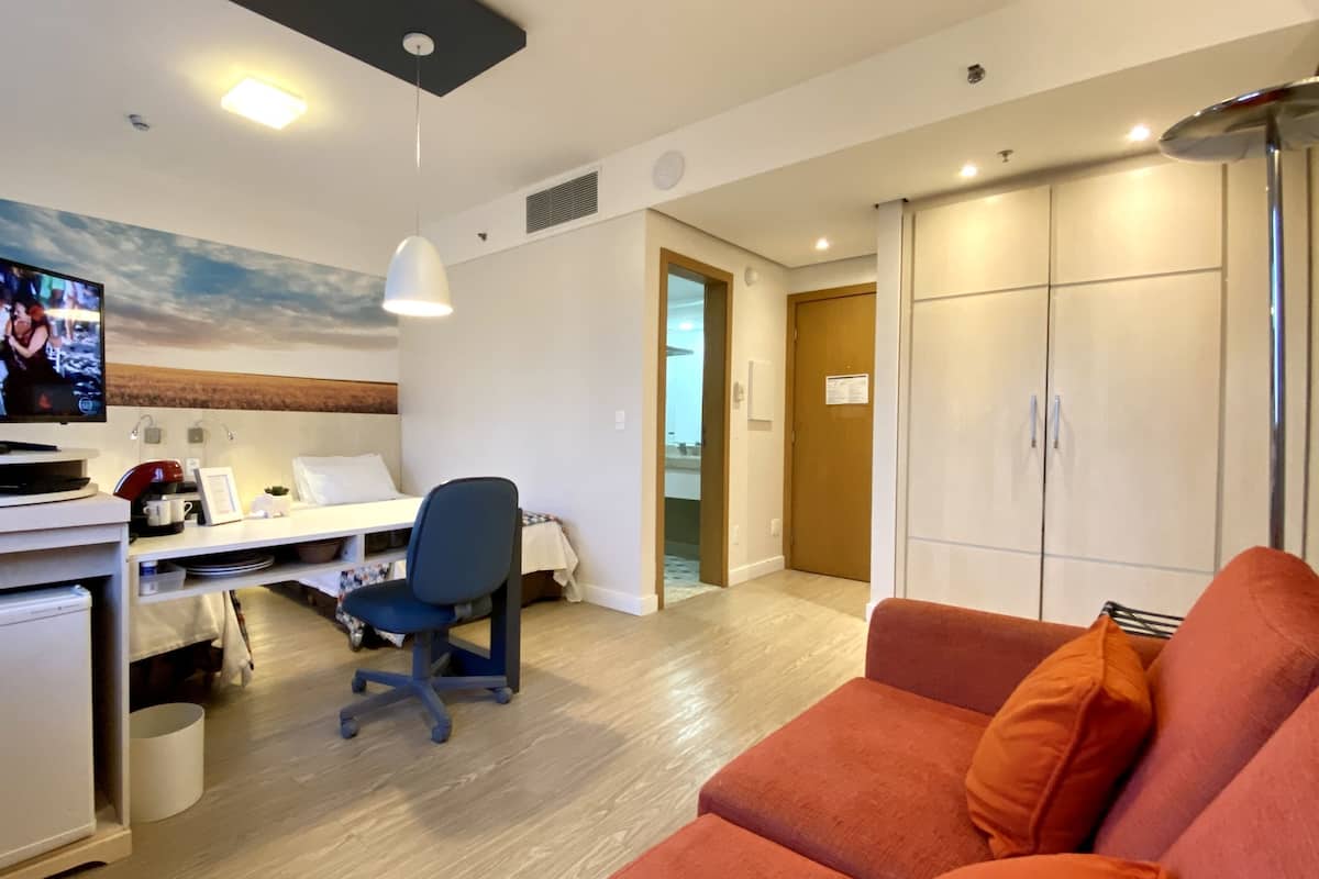 Hotellihuone, jossa on työpöytä, televisio, sohva ja vaatekaappi.