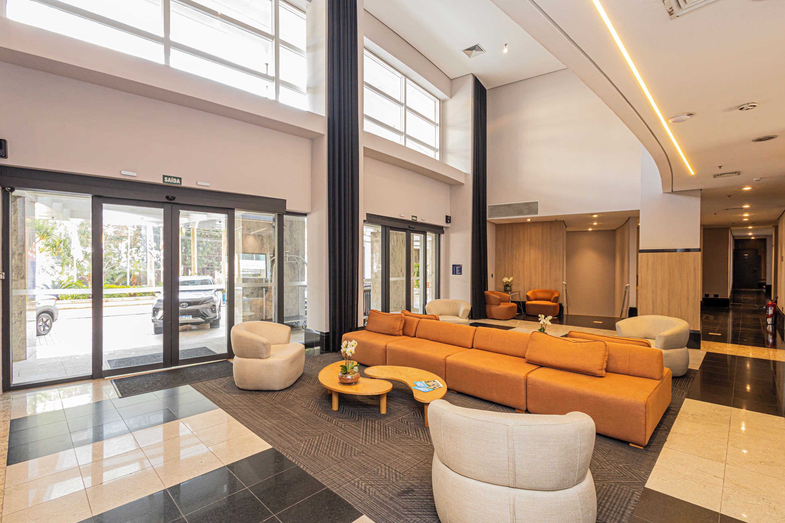 A spacious lobby with a large seating area, a reception desk, and a glass door entrance.