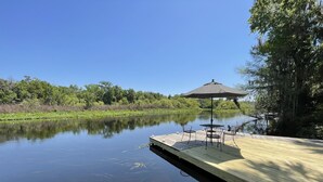 Un lago tranquilo con un muelle de madera, rodeado de exuberante vegetación y árboles.