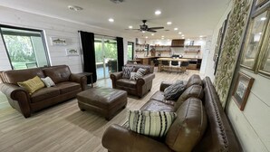 Una sala de estar amplia con sofás de cuero, una mesa de centro y un comedor con una cocina al fondo.
