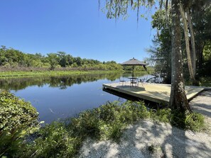 Un lac paisible avec une jetée en bois, une table, des chaises et un parasol.