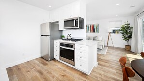 A modern kitchen with white cabinetry, stainless steel appliances, and a wooden floor.