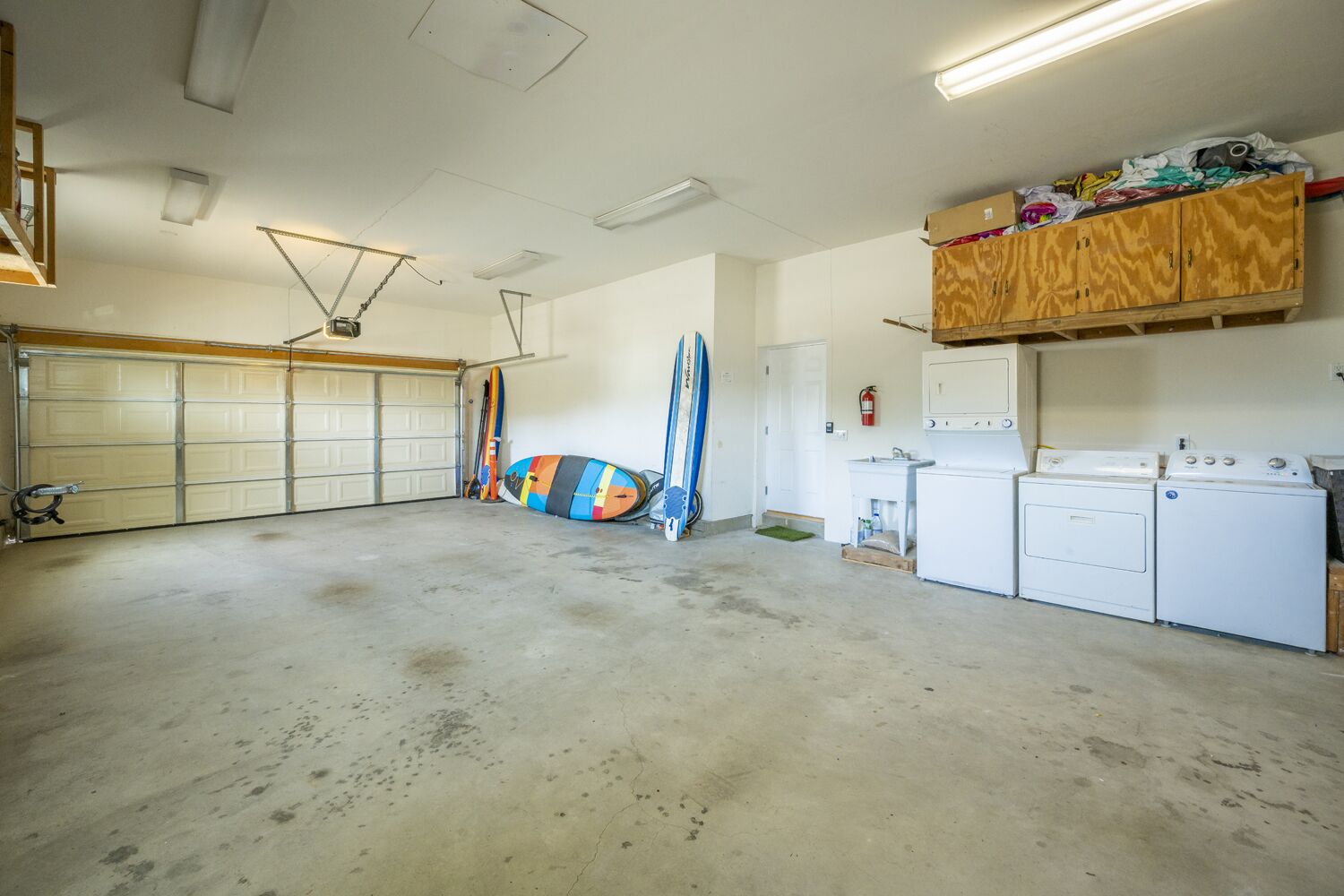 Ett garage med ett betonggolv, en arbetsbänk i trä, en tvättmaskin och surfbrädor.