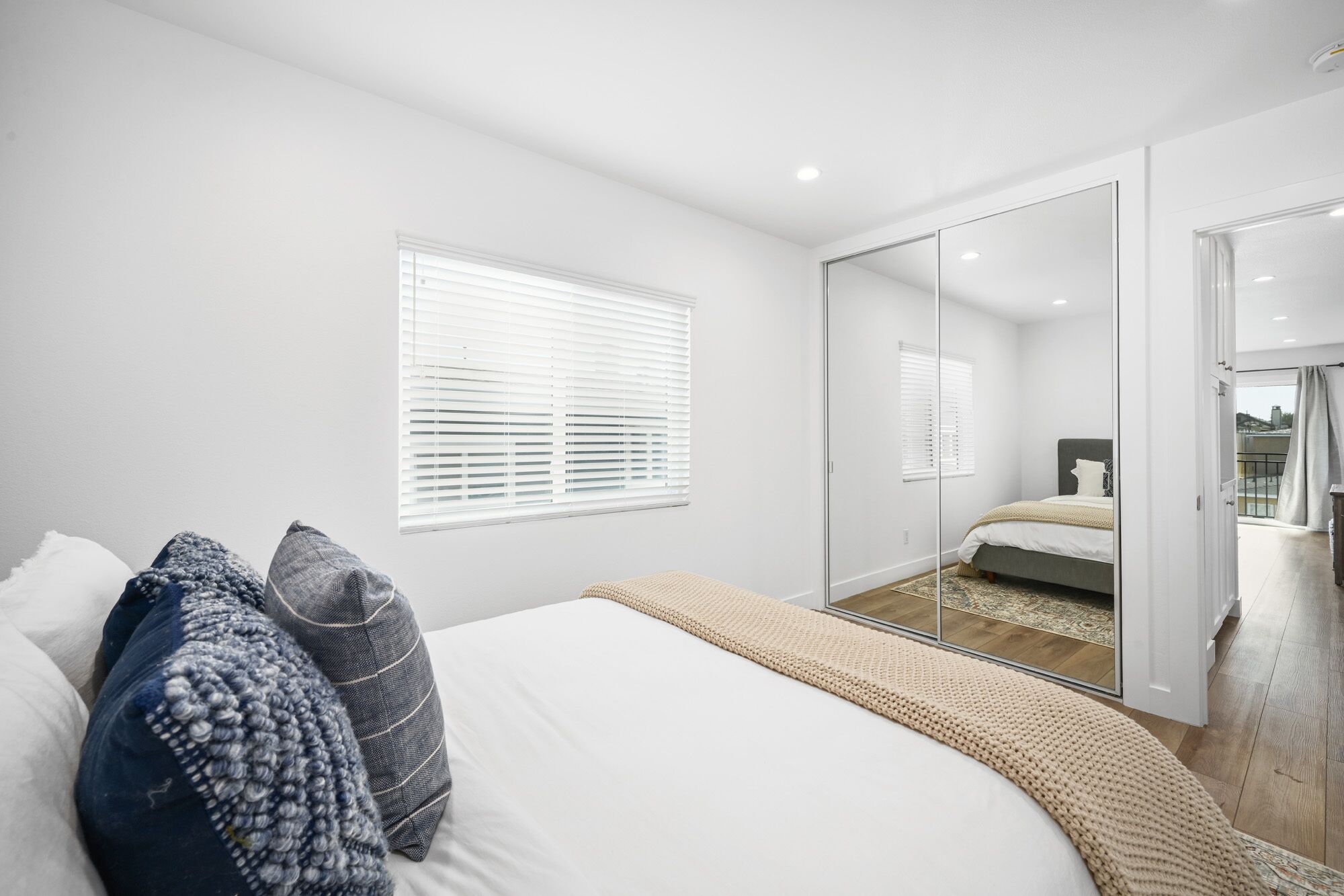 Un dormitorio con cama, un espejo grande y una puerta corrediza que da a un balcón.