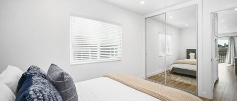 Un dormitorio con cama, un espejo grande y una puerta corrediza que da a un balcón.