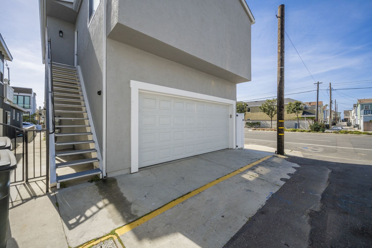 A residential building with a white garage door, a metal staircase, and a clear sky.