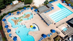 Luchtbeeld van een resort met een groot zwembad, meerdere loungegedeeltes met parasols, en een apart gedeelte voor een glijbaan.