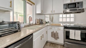 A modern kitchen with white cabinets, a stainless steel range, a microwave, and a toaster.