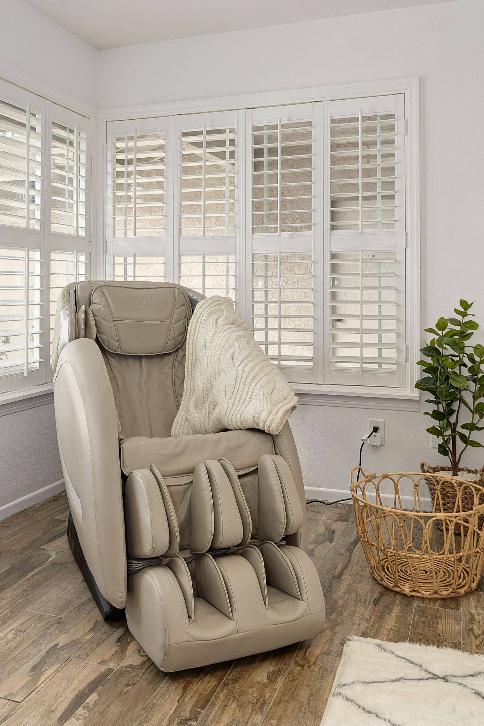 A massage chair in a room with large windows and a wicker basket.