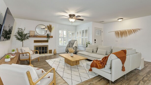 A modern living room with a white sofa, wooden coffee table, and a fireplace.