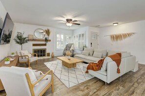 Un salon moderne avec un canapé blanc, une table basse en bois et une cheminée.