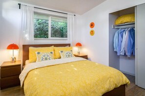 A bedroom with a bed, two bedside tables, a window with curtains, a nightstand, and a wardrobe. - #StayinMyDistrict Modern Mid-Century Retreat (Beaverton)