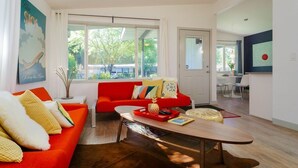 Un salon moderne avec un canapé rouge, une table basse en bois et une grande fenêtre donnant sur les arbres.