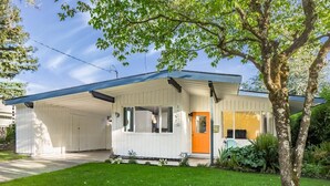 Une maison de plain-pied avec un porche couvert, une porte d’entrée et un petit jardin devant.