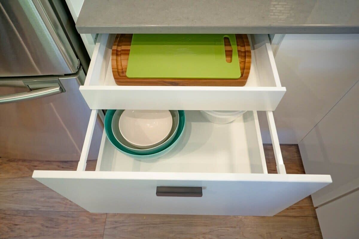 A kitchen drawer with a cutting board and a bowl.