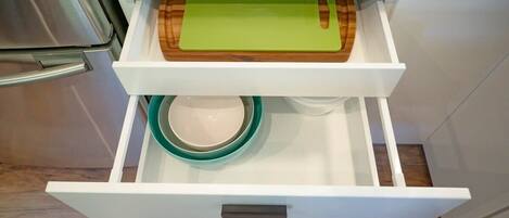 A kitchen drawer with a cutting board and a bowl.