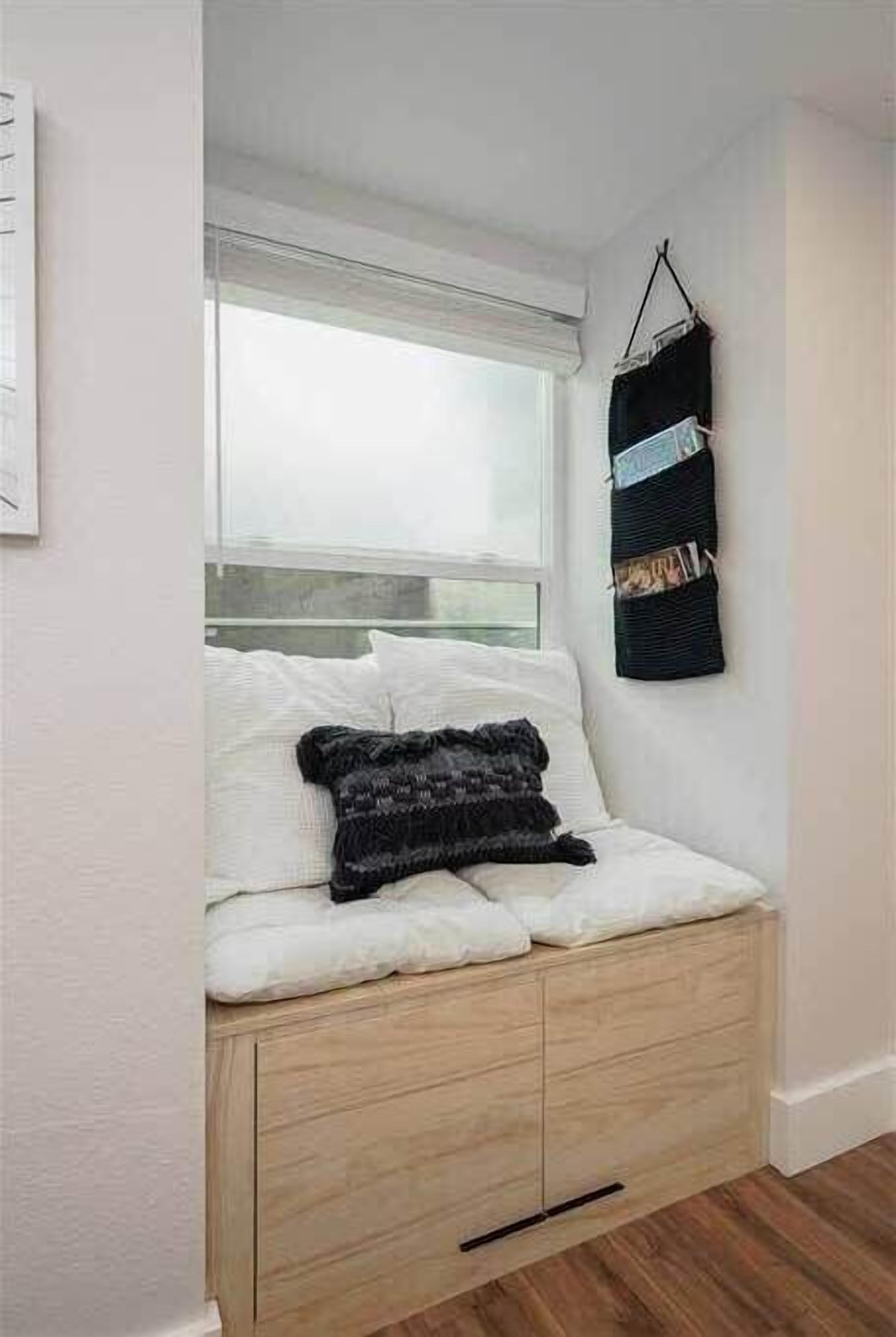 A small, cozy room with a bed, a window, and a wall-mounted storage unit.