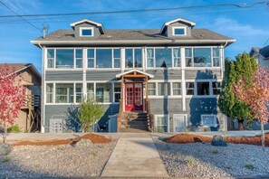 Stunning two-story home with a central entrance, flanked by windows, and a beautifully manicured garden.