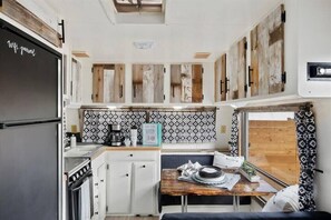 A compact kitchen with a stove, sink, and a dining area with a table and bench.
