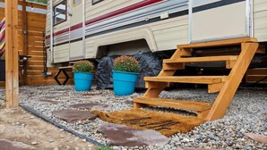 A campervan with a wooden deck, two blue flower pots, and a wooden ramp. - #StayinMyDistrict Twin Falls Backyard Glamper (Twin Falls)