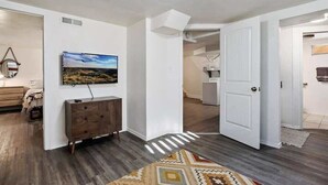 A modern living room with a wooden cabinet, a mounted TV, and a patterned rug. - #StayinMyDistrict Twin Falls Pendleton Chic Suite (Twin Falls)
