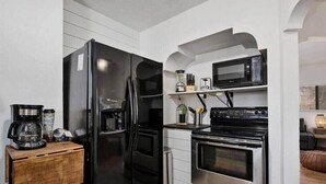 Une cuisine de taille réduite, avec un réfrigérateur noir, un four à micro-ondes et une cuisinière.