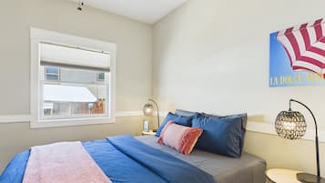 A bedroom with a bed, a window, a ceiling fan, a wall clock, and a decorative piece.