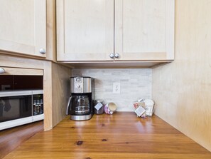 A kitchen with wooden cabinets, a coffee maker, a microwave, and a tiled backsplash.