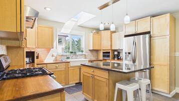 Une cuisine moderne avec des meubles en bois, des appareils en acier inoxydable et un grand îlot central doté de tabourets.