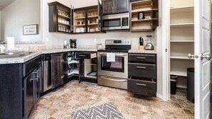 Una cocina moderna con armarios oscuros, electrodomésticos de acero inoxidable y piso de baldosas.