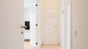 A hallway with a wooden floor, white walls, and a door at the end. - Stylish apartment in Middelkerke - 200m from the beach (Middelkerke)
