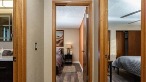A narrow hallway leading to a bedroom with a bed, a nightstand, and a lamp. - #StayInMyDistrict Eclectic Boise Townhouse near St. Als (Boise)