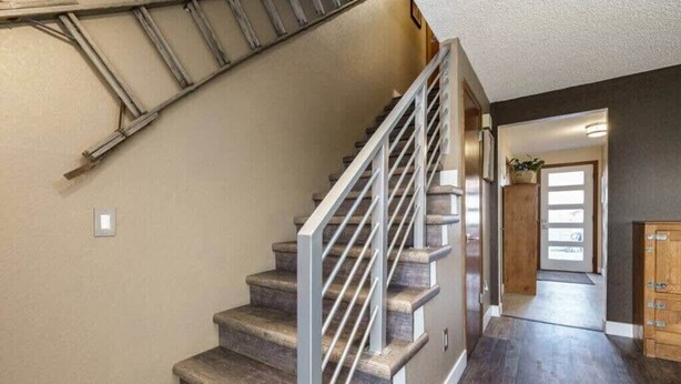 A staircase with a metal railing, wooden steps, and a dark floor. - #StayInMyDistrict Eclectic Boise Townhouse near St. Als (Boise)