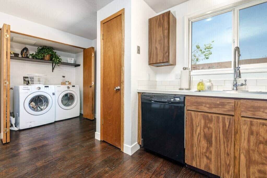 Una cocina compacta con armarios de madera, lavavajillas y lavadora.