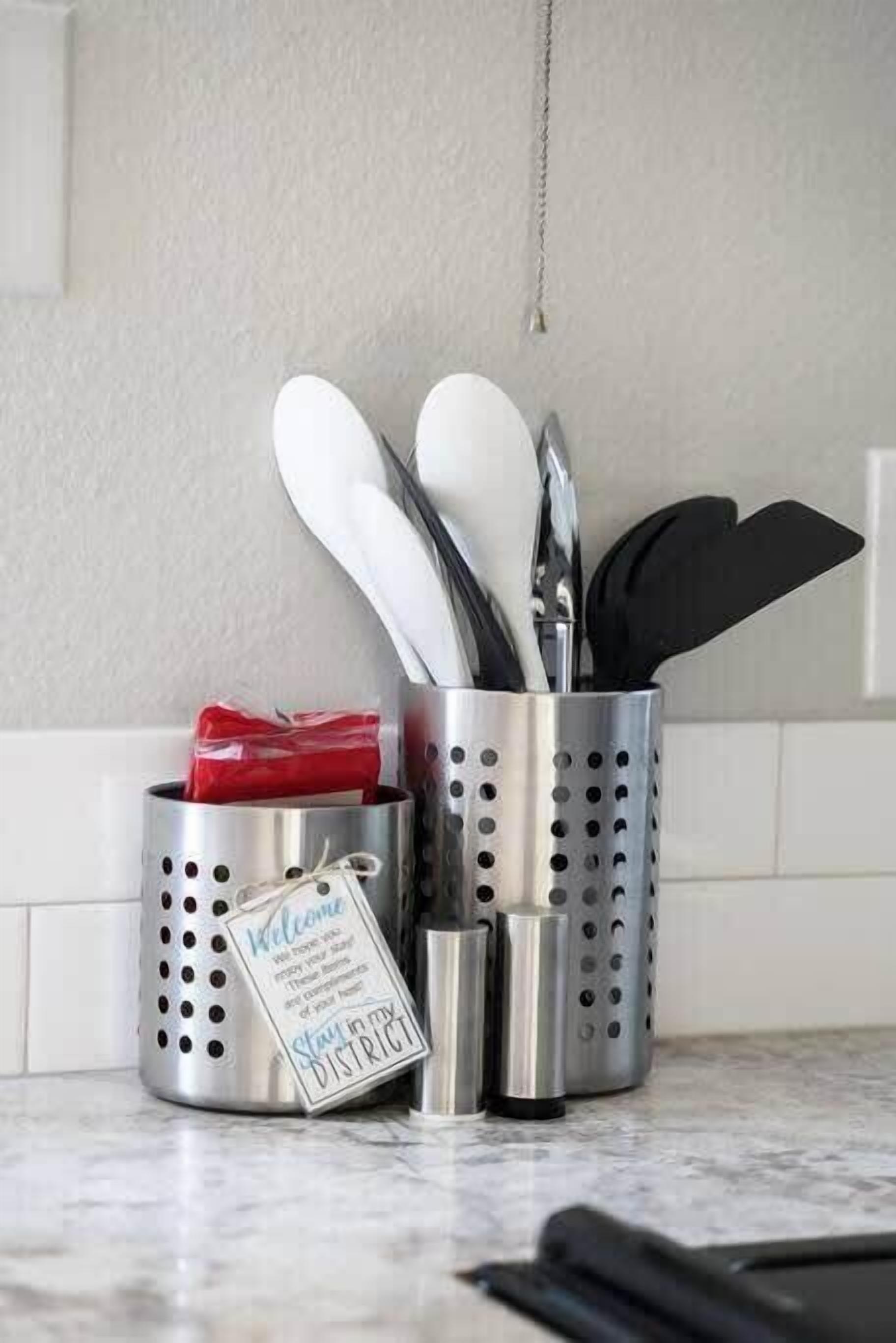 A kitchen utensil holder with a 'Welcome' sign and a 'Stay in my District' sign.