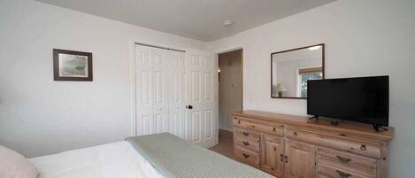 A bedroom with a bed, a dresser, a television, and a door.