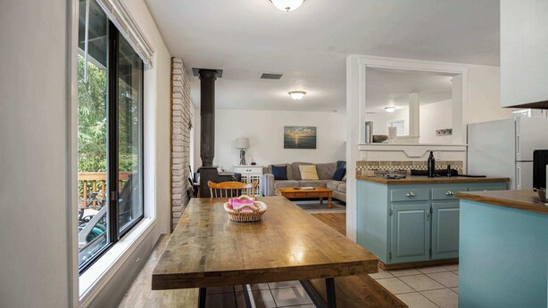 Una cocina con una mesa de madera, un armario azul y un ventanal con vistas a zonas verdes.